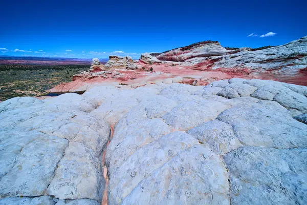 Beyaz kaya oluşumları, Ak Kol 'da, Vermilion Uçurumları Ulusal Anıtı' nda, Arizona Mermer Kanyonu 'ndaki derin mavi gökyüzünün altında canlı kırmızı kumtaşı katmanlarının üzerinde yükselir.
