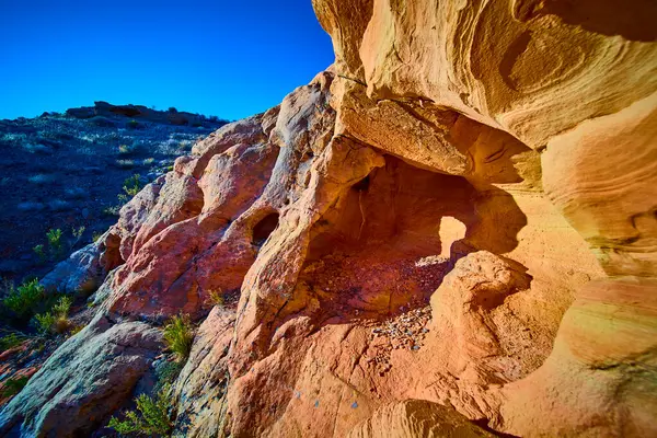Güneş ışığı alan kumtaşı mağarası ve yıpranmış kaya oluşumları Gold Butte Ulusal Anıtı Nevada 'nın kurak yamaçlarından yükseldi parlak mavi gökyüzünün altında