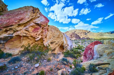 Çölün dibinden parlak kırmızı ve krem rengi kumtaşı kayalar yükseliyor. Nevada 'daki Gold Butte Ulusal Anıtı' nda dağınık çalılar ve dağlar var.