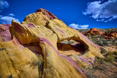 Pembe ve sarı kumtaşıyla göz kamaştırıcı Napolitan kemer oluşumu, Nevada 'daki Whitney Pocket Ulusal Anıtı' nda, parlak mavi gökyüzünün altında.