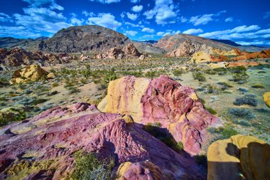 Whitney Pocket Nevada 'da dinamik bir gökyüzü altında canlı kumtaşı kayaları ve engebeli dağlar Gold Butte Ulusal Anıtı ve kurak Amerikan Güneybatısı' nın eşsiz güzelliğini yakalıyor.