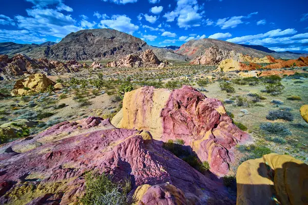 Whitney Pocket Nevada 'da dinamik bir gökyüzü altında canlı kumtaşı kayaları ve engebeli dağlar Gold Butte Ulusal Anıtı ve kurak Amerikan Güneybatısı' nın eşsiz güzelliğini yakalıyor.
