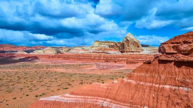 Catstair Canyon Utah yakınlarındaki Kanyon Noktası 'nda çarpıcı bir tepe ve fırtınalı gökyüzü ile dramatik kırmızı ve beyaz kumtaşı uçurumlarının havadan görünüşü Amerikan güneybatısının engebeli güzelliğini vurguluyor..