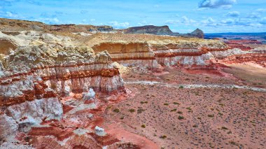 Utah Kanyon Noktası 'ndaki canlı kayalıkların havadan görünüşü. Amerika' nın güneybatısındaki geniş açık gökyüzünün altında kurak çöl tabanından yükselen kırmızı ve turuncu kaya oluşumları.