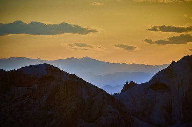 Kaya oluşumları ve uzak Nevada dağları Whitney Pocket ABD yakınlarındaki Gold Butte Ulusal Anıtı 'nda gün batımının altın saatinde gökyüzünün altında parıldıyor.