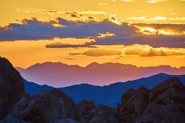 Altın saat gün batımı Nevada 'daki Altın Butte Ulusal Anıtı' nı aydınlatacak. Engebeli Whitney Pocket kayaları, katmanlı dağlar ve parlayan gökyüzü.