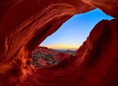 Kırmızı kumtaşı kemeri engebeli çöl arazisinin panoramik manzarasını ve gündoğumunda Whitney Pocket Nevada yakınlarındaki Gold Butte Ulusal Anıtı 'nda açık gökyüzünü çerçeveler.