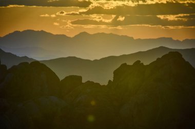 Ilık güneş ışığı, katmanlı dağların ve kayalık arazinin üzerinde parıldıyor. Golden Butte Ulusal Anıtı Nevada 'da gün batımında Whitney Pocket' in sakin havasını yakalıyor.