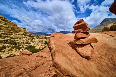 Dengeli bir kaya yığını Las Vegas yakınlarındaki Red Rock 'ın Calico bölgesinde geniş açık çöl ve geniş gökyüzü tarafından çerçevelenmiş kırmızı kumtaşının üzerinde duruyor..