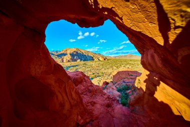 Nevada 'daki Gold Butte Ulusal Anıtı' nda çarpıcı bir kemer oluşumu, açık mavi gökyüzü altında engebeli Whitney Pocket arazisi ve canlı çöl renklerini gözler önüne seriyor.