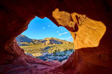 Kırmızı kumtaşı kemeri oluşumu, Nevada Ulusal Anıtı 'nda geniş bir çöl manzarası oluşturur. Altın saat gün batımı ışığı engebeli araziyi ve canlı gökyüzünü güçlendirir.