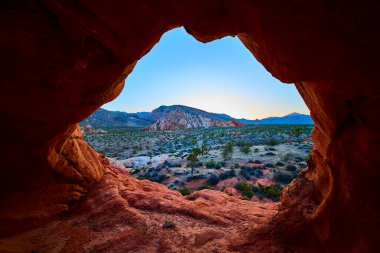 Kızıl kaya kemeri oluşumu engebeli çöl ve dağları çerçeveler. Nevada Altın Butte Ulusal Anıtı. Açık gökyüzünün altında Whitney Pocket görülebiliyor.