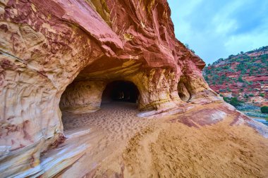 Utah 'taki Kanab Kum Mağaraları' ndaki dramatik kumtaşı mağarası çarpıcı kırmızı ve altın katmanlar ve kemerli girişlerle manzaralı güneybatı çöl manzarasına macera davet ediyor.