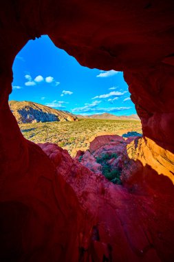 Gold Butte Ulusal Anıtı 'ndaki Whitney Pocket' da dramatik kırmızı kumtaşı oluşumu Nevada engebeli çöl manzarasını ve parlak mavi gökyüzünün altındaki uzak dağları çerçeveler.