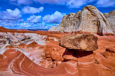 Dengeli kaya büyüsü Utahs Toadstool Hoodoos 'daki çizgili kumtaşının tepesinde duruyor dramatik çöl tepeleri ve Amerika' nın güneybatısında şişkin bulutlarla dolu bir gökyüzünün altında beyaz bir uçurum.