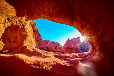 Altın saat güneş ışığı, Nevada Ulusal Anıtı 'nda doğal bir kemer oluşumundan akar. Kırmızı kayaları aydınlatır ve canlı bir günbatımı sahnesi yaratır.