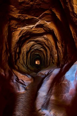 Kanab Utah 'taki Ejderha Mağarası' nın düşük perspektifli görüntüsü engebeli bir kumtaşı tüneli gösteriyor. Duvarları ılık ışıkla yıkanmış, keşif macerası ve güneybatı gizemini çağrıştırıyor.