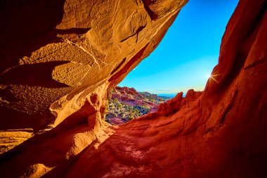Canlı kırmızı kaya kemeri oluşumu, açık mavi gökyüzünün altında Whitney Pocket Nevada yakınlarındaki Gold Butte Ulusal Anıtı 'ndaki çöl manzarasının güneşli bir görüntüsünü oluşturur.
