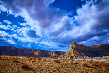 Alstrom Point Utah 'taki kurak çölün üzerinde yükselen kumtaşı tepesi dramatik bulutlar ve altın saat ışığı Amerika' da nefes kesici bir güzellik ve yalnızlık manzarası yaratıyor.