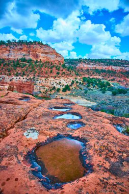 Yağmur suları mavi gökyüzünü ve Kanab Kum Mağarası Utah 'taki kırmızı kumtaşının üzerindeki bulutları yansıtır. Dramatik kanyon manzaraları ve engebeli Güneybatı güzelliği Amerika Birleşik Devletleri 'nde macera ve doğa harikasının altını çiziyor..