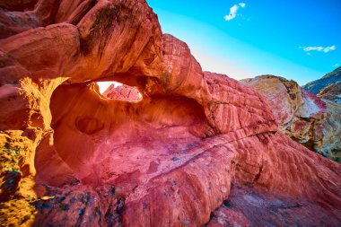 Canlı kırmızı kumtaşı kemeri oluşumu dokulu kayalara ve Nevada 'daki Altın Göt Ulusal Anıtı' nda açık mavi gökyüzüne karşı duruyor Whitney Pocket ve dramatik çöl jeolojisini gözler önüne seriyor.