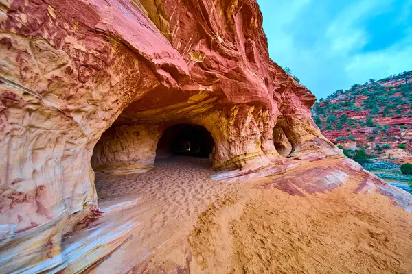 Utah 'taki Kanab Kum Mağaraları' ndaki dramatik kumtaşı mağarası çarpıcı kırmızı ve altın katmanlar ve kemerli girişlerle manzaralı güneybatı çöl manzarasına macera davet ediyor.