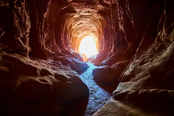 Güneş ışığı Kanab Utah yakınlarındaki Ejderha Mağarası 'na akıyor. Kum taşından örülmüş duvarları vurguluyor. Macera araştırmalarına davetiye çıkaran dolambaçlı bir yol.
