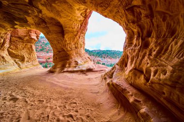 Kanab Kum Mağarası 'ndaki kumtaşı kemerlerinden akan güneş ışığı, Amerika' nın güneybatısında macera ve merak uyandıran kumdaki çarpıcı çöl manzarasını ve ayak izlerini çerçeveliyor.