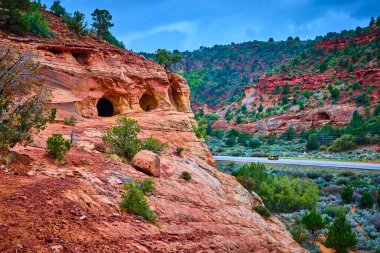 Sarı bir araba Kanab Utah yakınlarındaki dramatik kırmızı kumtaşı uçurumlarını ve mağara açılışlarını geçerek Kum Mağaralarının engebeli güzelliğini ve Amerika 'nın güneybatısındaki yol macerasının ruhunu gözler önüne seriyor.