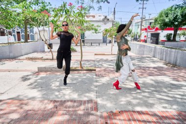 İki genç LGBT dansçısı şehir caddesinde vogue koreografisi yapıyor.                       