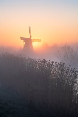 Bahar sisinde geleneksel bir Hollanda yel değirmeninde şafak vakti.