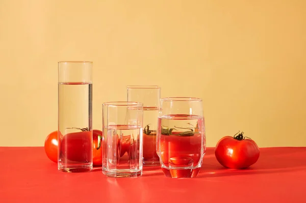 Transparenta Glas Vatten Placeras Framför Saftiga Röda Tomater Mot Röd — Stockfoto