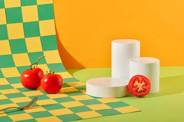 ジューシーな赤いトマトは ホワイトプラットフォームの隣にあります ターコイズと黄色のチェッカーパターンのユニークな背景 天然化粧品を展示するための空きスペース — ストック写真