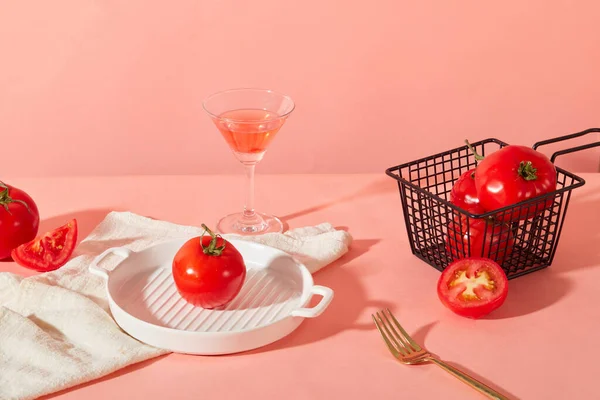 ピンクの背景には 新鮮なトマト ワイヤーメッシュバスケット セラミックトレイ カクテルグラス タオルがあります トマトの主成分を含む製品を展示するスペース — ストック写真