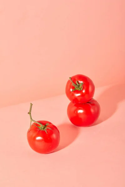 ピンクの背景に隔離されたジューシーな赤いトマトの近く トマトは骨を健康に保ち 骨粗鬆症を予防するのに役立つビタミンKとカルシウムが含まれています — ストック写真