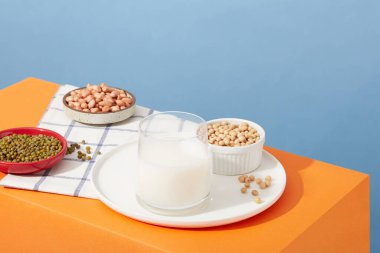 Soya fasulyesi, fıstık ve yeşil fasulye tabaklar ve bir kase içinde bulunur. Fındık sütüyle doldurulmuş cam bardak. Farklı türde fındıklar biraz daha farklı mikro besin içerir.