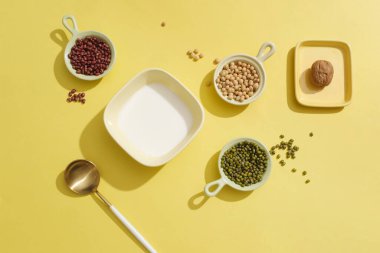 Süt kırmızı fasulye, soya fasulyesi, yeşil fasulye ve bir kaşıkla çevrili bir kasenin içinde. Tabakta sergilenen bir ceviz. Sağlıklı organik gıda konsepti