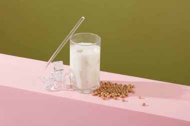 Süt kabı, pipet ve biraz buzla süslenmiş soya fasulyesi yığını. Soya sütündeki vitaminler, mineraller ve antioksidanlar önemli sağlık faydaları sağlayabilir.