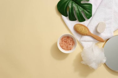 Bazı vücut bakım ürünleriyle süslenmiş pembe himalaya tuzu içeren bir seramik kase. Süslemeli yeşil bir yaprak. Kopya alanı olan bej arkaplan. Pembe Himalaya tuzu banyo tuzlarında kullanılır.