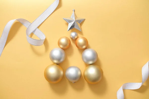 黄色の背景にカラフルなクリスマスボールと装飾が施されたお祝いのフレーム かわいいバブルは 上部に星がついた三角形に配置されています トップビュー — ストック写真