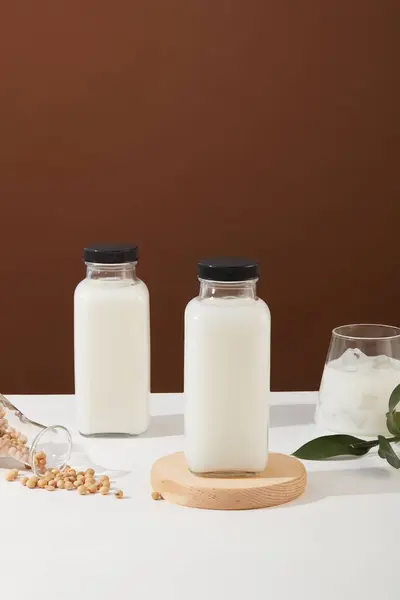 Two blank label bottle of soy milk decorated with many soybeans and a milk cup. Soybean (Glycine max) can help support healthy muscles and organs
