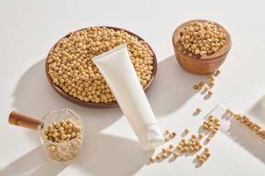 Birçok soya tohumu ahşap tabak ve kâsede bulunur. Boş etiket tüpü sergileniyor. Soya fasulyesi (Glicine max) antioksidan özellikleri için pozitif araştırma desteğine sahiptir