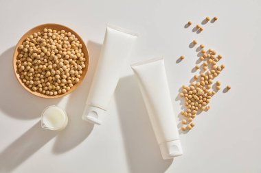 Soya fasulyesi kabı, ahşap bir tabak soya fasulyesi ve markasız kozmetik tüplerle düzenlenmiş soya sütü. Cilt bakımı markalaşmasının konteyner paketi