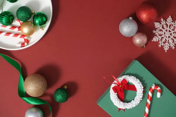 用可爱的装饰品装饰圣诞假期的想法 色彩艳丽的灌木 糖果手杖 彩带和礼品盒摆放在红色的背景上 顶部视图 带有复制空间的广告场景 — 图库照片