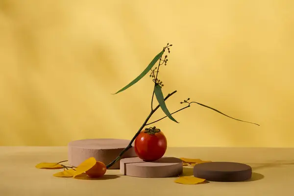 秋のコンセプトの広告製品のためのミニマリストアートの背景 赤い熟したトマトで飾られた3つのシリンダー表彰台は 自然な影の葉で黄色の背景に残ります フロントビュー — ストック写真