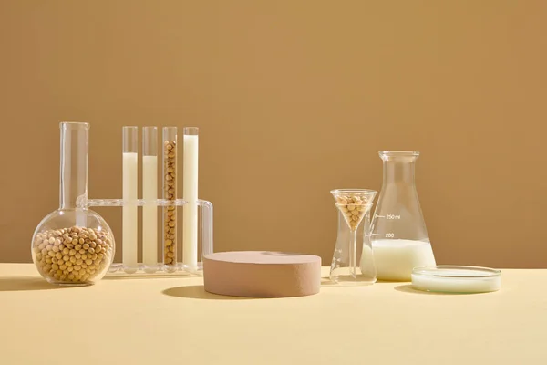 Some types of laboratory glassware containing soybean seeds and milk arranged with a brown podium. Pedestal or platform for beauty products presentation