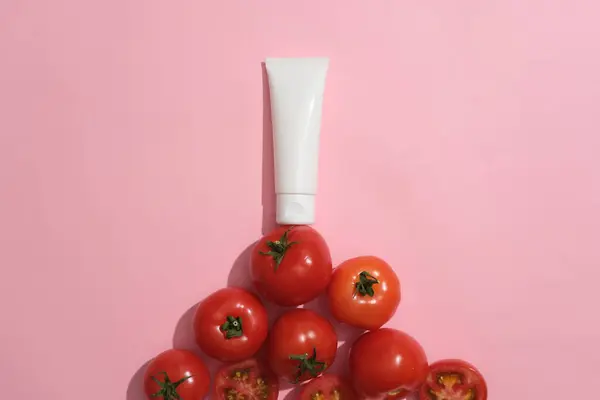 Pusta Etykieta Tubka Kosmetyczna Kolorze Białym Stojąca Stosie Pomidorów Różowe — Zdjęcie stockowe