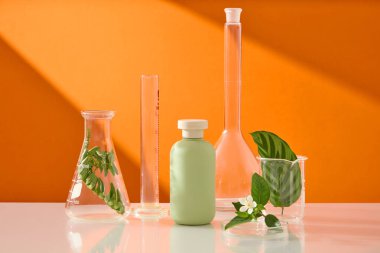 Turuncu arka planda birkaç çeşit laboratuvar vitriniyle süslenmemiş pastel bir şişenin ön görüntüsü. Cilt bakımı güzellik kozmetik tüpü.