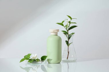 Petri kabı ve Erlenmeyer şişesi ile süslenmiş yeşil renkli etiketsiz bir şişenin ön görüntüsü. Cilt bakımı kozmetik ürünleri için markalaşma şişesi