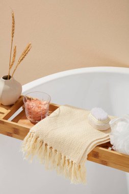 Küvetli doğal kozmetik kavramında banyo süngeri, ayak fırçası ve bir bardak pembe himalaya tuzu vardı. Ürününüzü göstermek için bej eşarptaki boşluk
